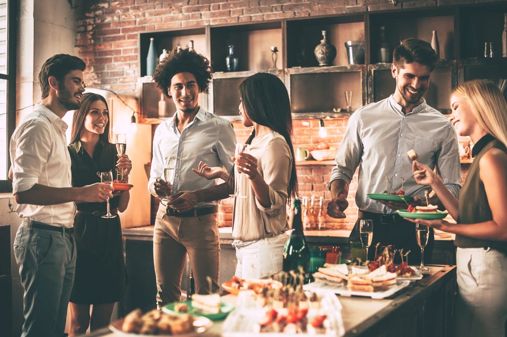 Amigos a comer petiscos e beber champanhe numa festa, contexto de consumo excessivo de álcool e alimentos processados