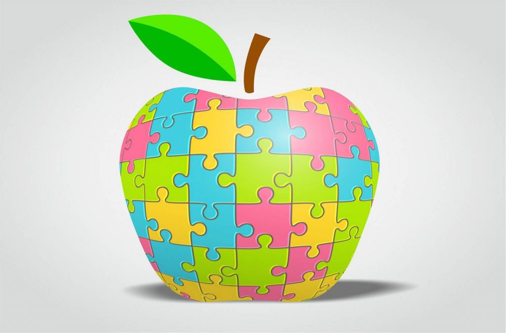 Maçã colorida feita de peças de puzzle, símbolo visual da nutrição no autismo, usada em conteúdo sobre alimentação