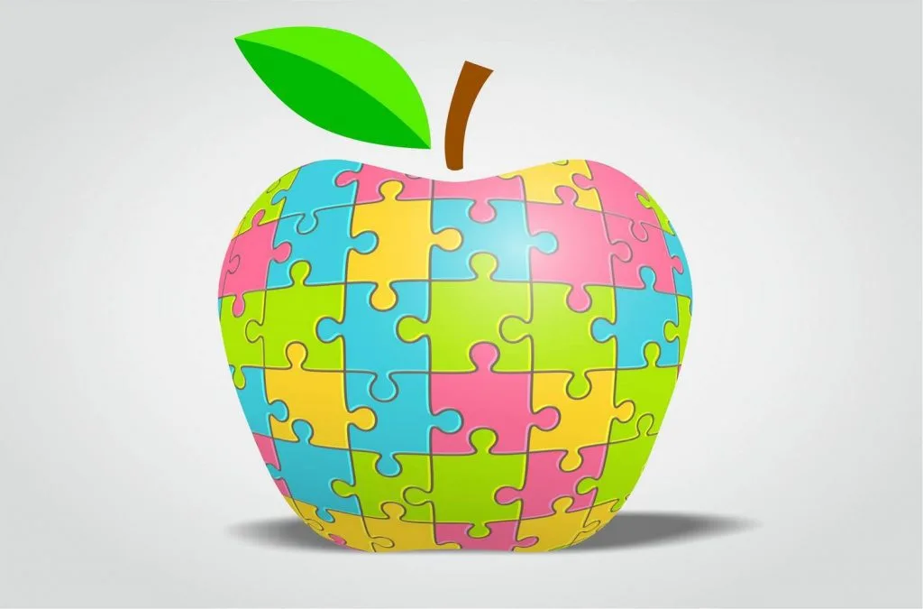 Maçã colorida feita de peças de puzzle, símbolo visual da nutrição no autismo, usada em conteúdo sobre alimentação
