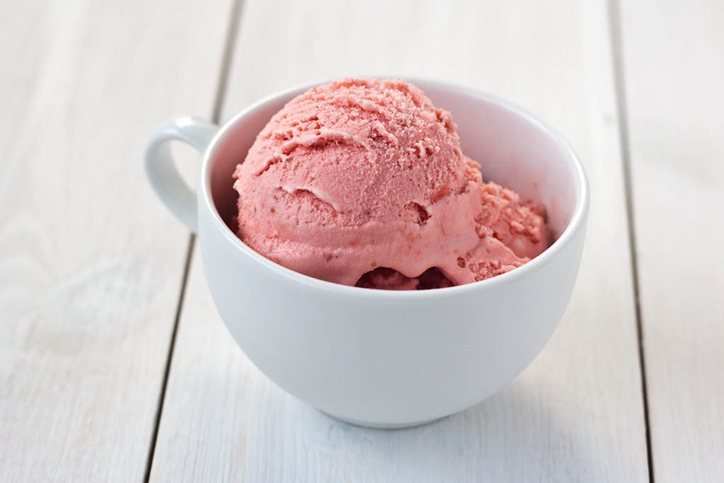 Gelado de morango sem açúcar, rico em antioxidantes, servido em taça branca sobre madeira clara — opção saudável