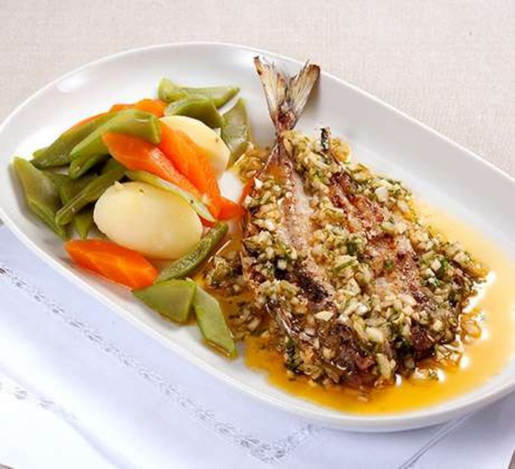 Peixe grelhado com ervas, acompanhado de feijão verde, cenoura e batata cozida, num prato branco