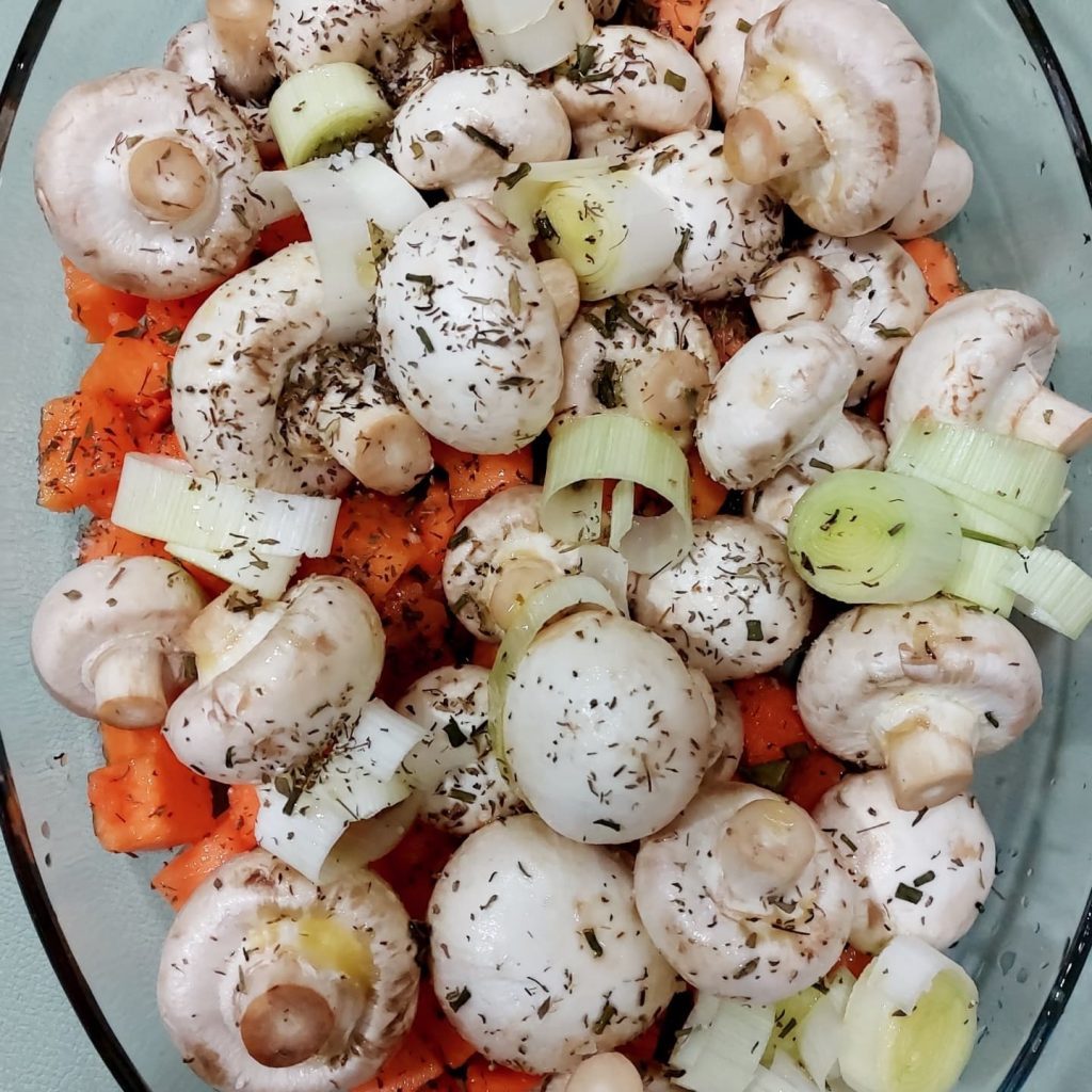 Cogumelos, cenoura e cebola temperados com ervas em vidro, prontos a cozinhar como refeição equilibrada e saudável