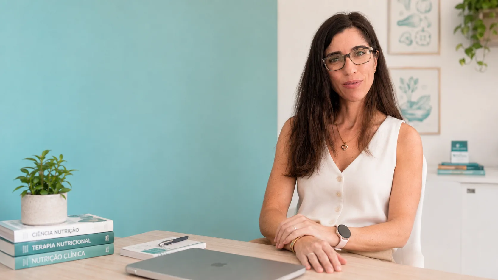 Secretária do consultório com livros de nutrição clínica e o computador de trabalho.